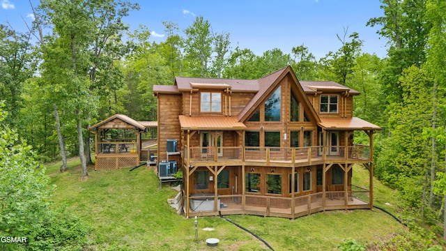 rear view of house featuring central air condition unit, a wooden deck, and a lawn