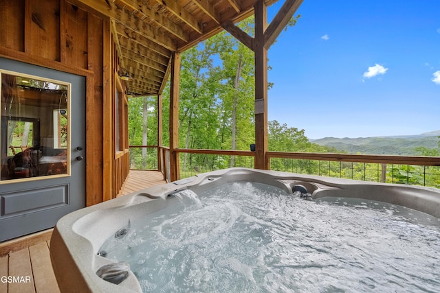 wooden deck with a mountain view and a hot tub