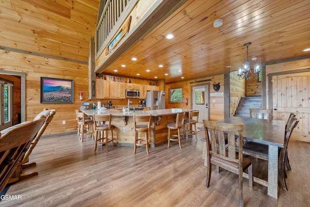 dining area featuring an inviting chandelier, light wood-style floors, wood walls, and recessed lighting