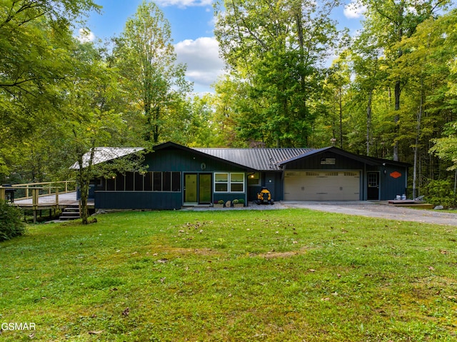 view of front of property featuring a sunroom, a garage, and a front yard