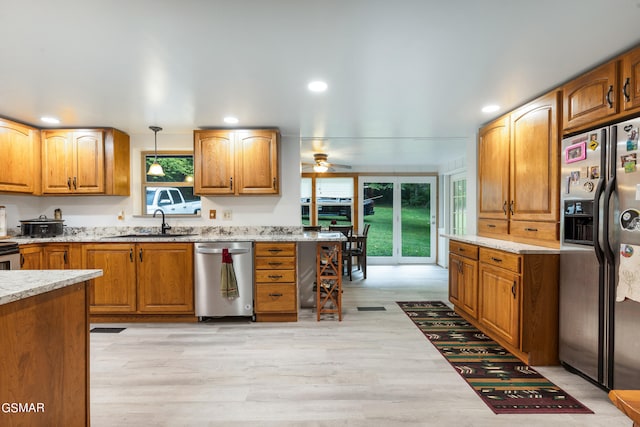 kitchen with stainless steel appliances, ceiling fan, sink, pendant lighting, and light hardwood / wood-style floors