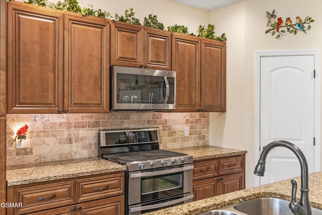 2159 Frewin Ct, Sevierville, TN 37876 - kitchen featuring stainless steel appliances, decorative backsplash, light stone counters, and brown cabinetry