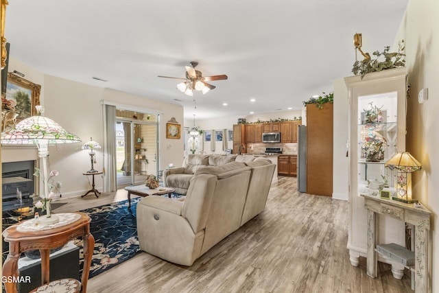 2159 Frewin Ct, Sevierville, TN 37876 - living area featuring ceiling fan, light wood-style floors, a glass covered fireplace, and recessed lighting