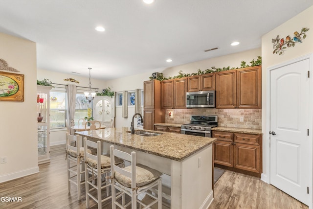 2159 Frewin Ct, Sevierville, TN 37876 - kitchen featuring appliances with stainless steel finishes, brown cabinets, light stone countertops, light wood-style floors, and tasteful backsplash