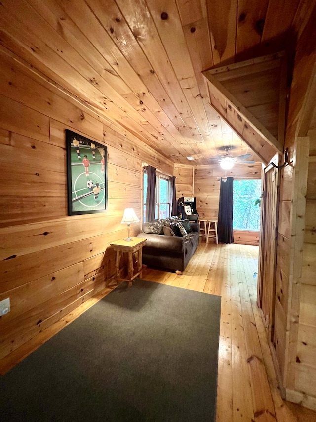 interior space with light hardwood / wood-style flooring, ceiling fan, wood walls, and wood ceiling