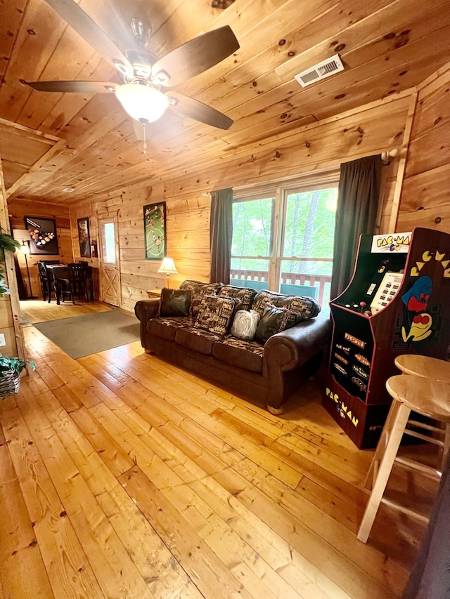 living room featuring light wood-type flooring, ceiling fan, wooden walls, and wood ceiling