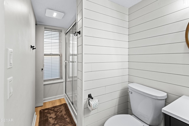 bathroom featuring wood finished floors, a stall shower, vanity, and toilet