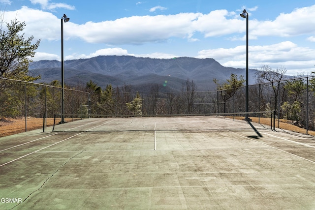 view of sport court featuring fence and a mountain view