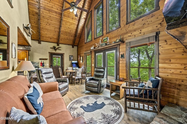 living area with ceiling fan, wooden ceiling, light wood-style flooring, wood walls, and beam ceiling