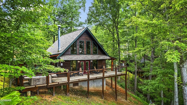 back of property featuring roof with shingles and a deck