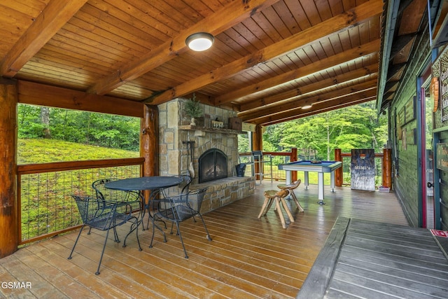 wooden terrace featuring an outdoor stone fireplace and outdoor dining area