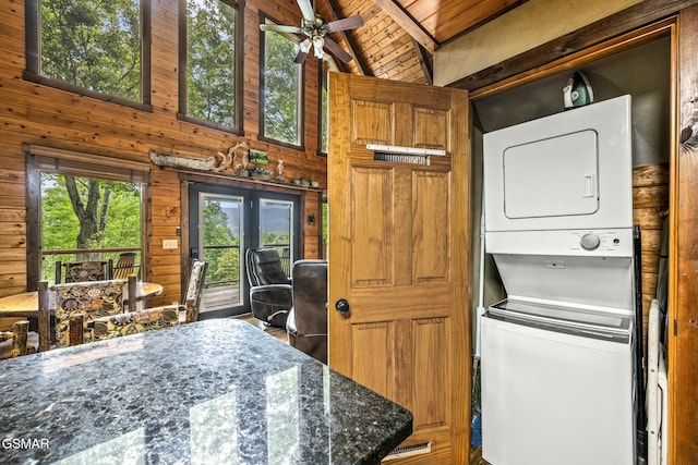 laundry area with laundry area, wooden walls, stacked washer / dryer, wooden ceiling, and a high ceiling