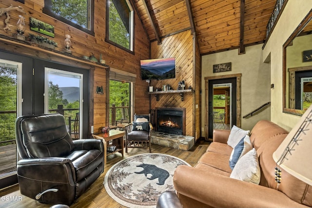living area with lofted ceiling with beams, a stone fireplace, wooden walls, wood finished floors, and wood ceiling