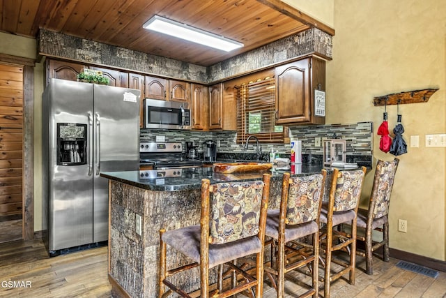 kitchen with appliances with stainless steel finishes, dark countertops, wooden ceiling, and decorative backsplash