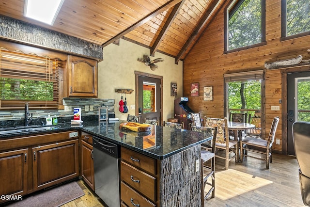 kitchen with beam ceiling, stainless steel dishwasher, wood ceiling, a sink, and dark stone counters