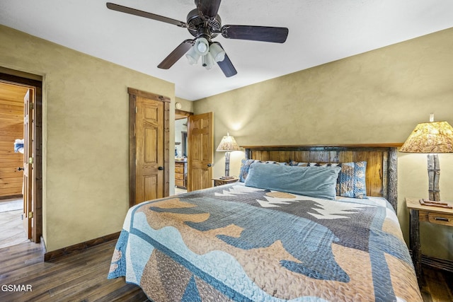bedroom featuring a textured wall, dark wood finished floors, baseboards, and ceiling fan