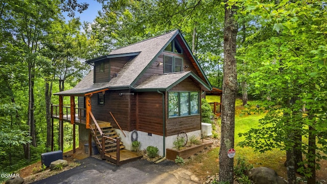 exterior space featuring roof with shingles, stairway, and central air condition unit