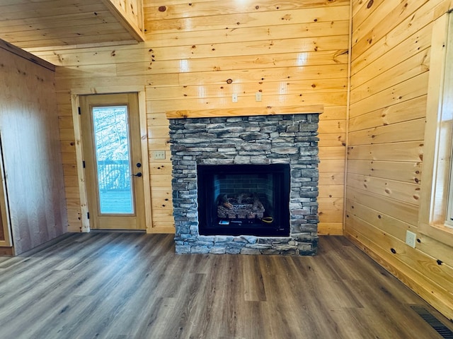 unfurnished living room with a stone fireplace, wooden walls, and dark hardwood / wood-style floors