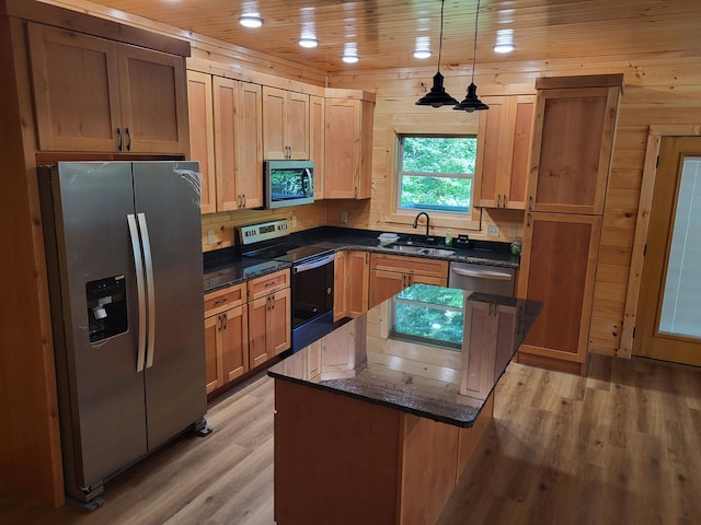 kitchen with sink, hanging light fixtures, stainless steel appliances, a center island, and light hardwood / wood-style floors