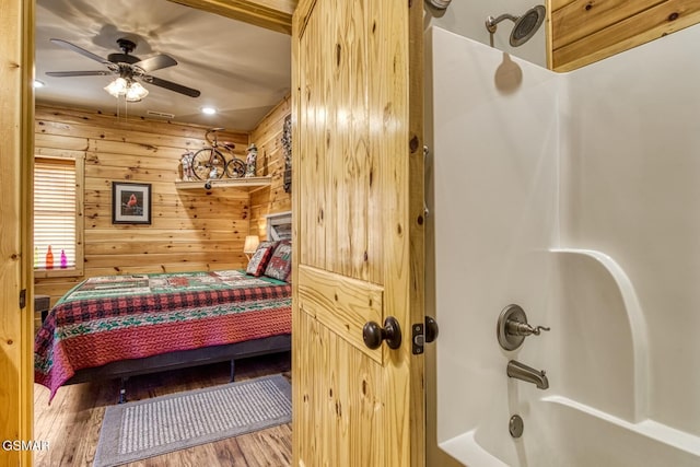 bedroom with wood-type flooring, ceiling fan, and wood walls