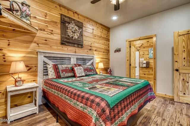 bedroom featuring hardwood / wood-style flooring, ceiling fan, and wooden walls