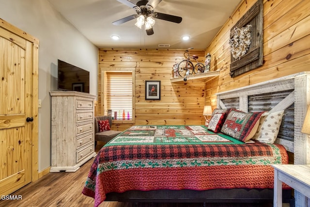 bedroom featuring wood walls, ceiling fan, and wood-type flooring