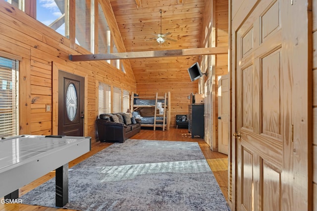 interior space featuring wood walls, wood ceiling, high vaulted ceiling, ceiling fan, and light hardwood / wood-style floors