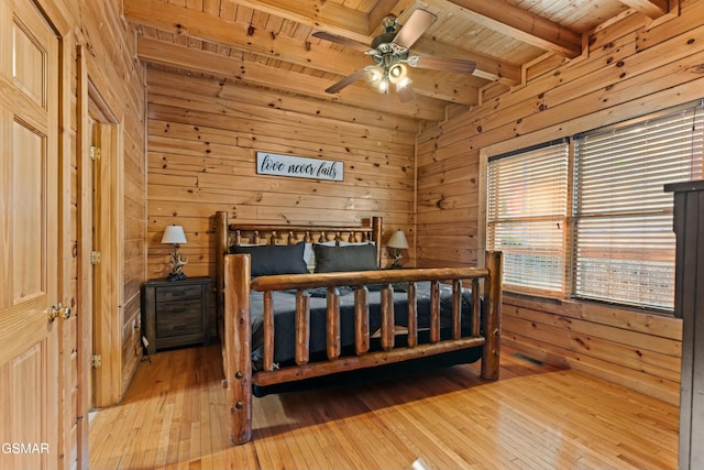 bedroom with light hardwood / wood-style floors, wood ceiling, beam ceiling, and wood walls