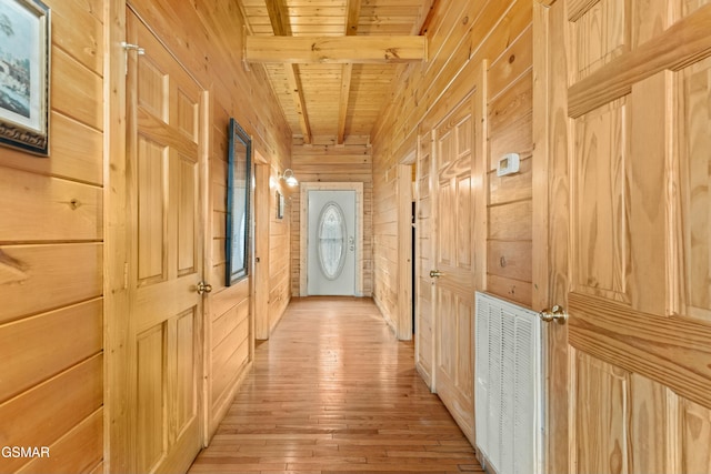 interior space with beamed ceiling, light wood-type flooring, wood ceiling, and wood walls