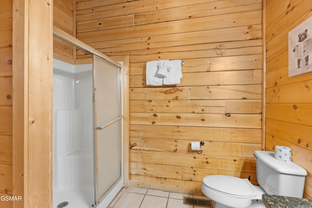 bathroom with a shower with door, tile patterned floors, wooden walls, and toilet