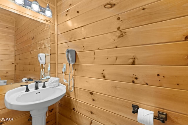 bathroom featuring sink and wooden walls