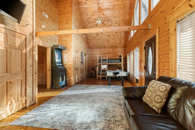 living room with hardwood / wood-style flooring, high vaulted ceiling, ceiling fan, and wood walls