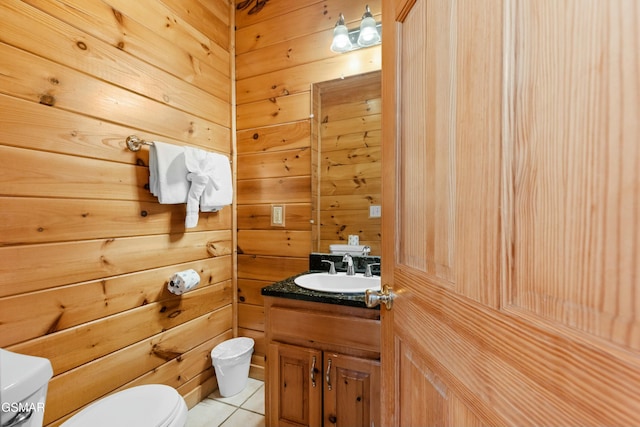 bathroom featuring vanity, wooden walls, tile patterned floors, and toilet