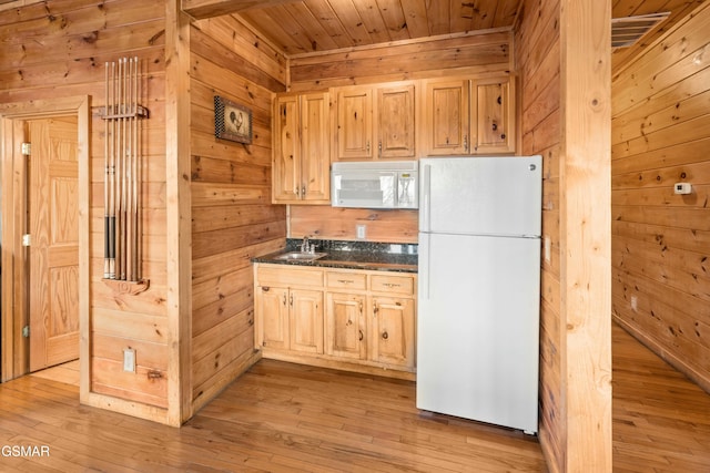 kitchen with white appliances, wooden walls, and light brown cabinets