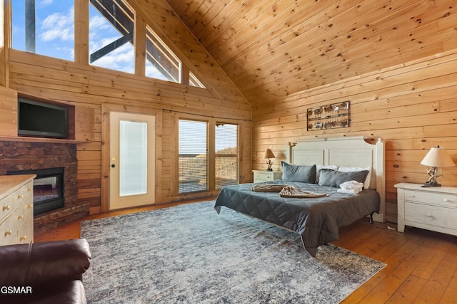 bedroom with hardwood / wood-style flooring, wooden ceiling, a stone fireplace, and wood walls