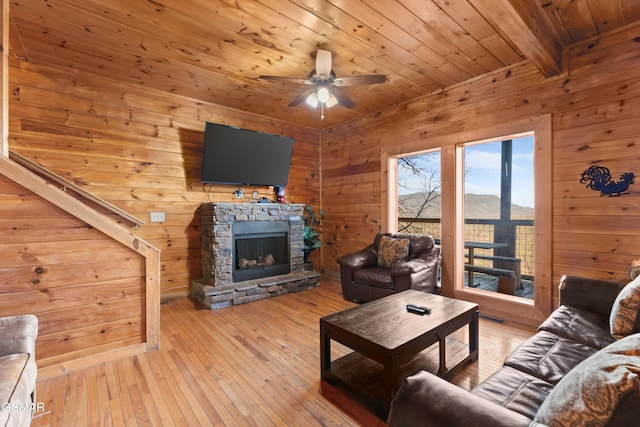 living room featuring light hardwood / wood-style flooring, a fireplace, wood ceiling, and wood walls