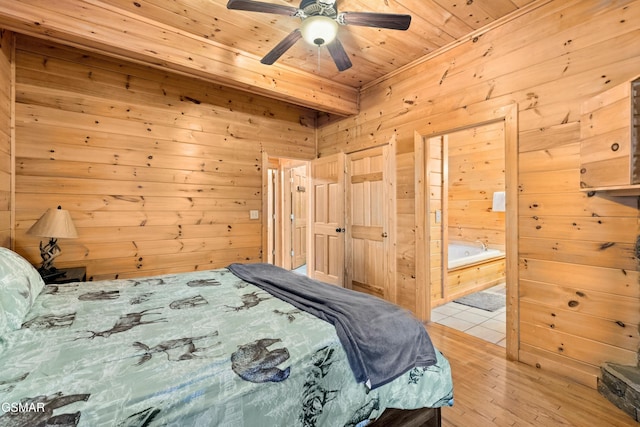 bedroom with connected bathroom, wood walls, wooden ceiling, ceiling fan, and light hardwood / wood-style floors