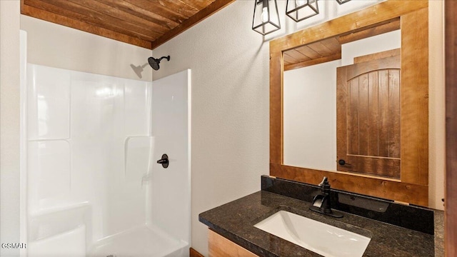 full bath featuring walk in shower, wooden ceiling, a textured wall, and vanity