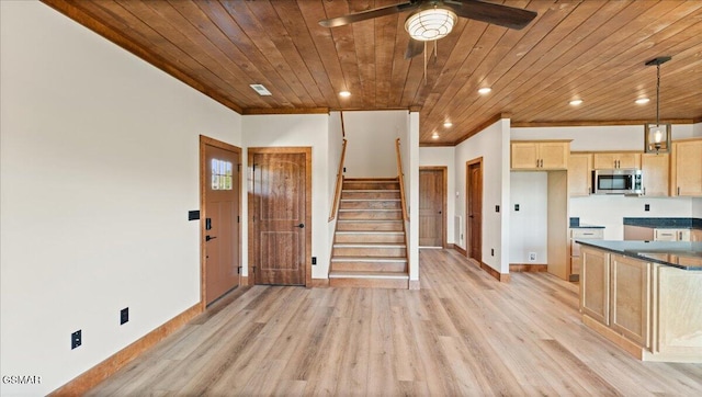 kitchen featuring wood ceiling, stainless steel microwave, light brown cabinetry, and baseboards