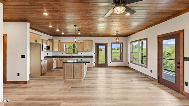 kitchen featuring stainless steel microwave, a sink, baseboards, and wood ceiling