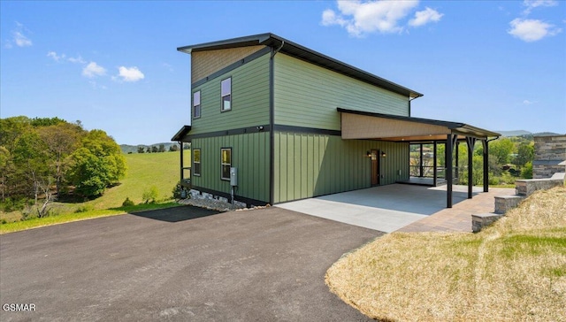 view of side of property with driveway, board and batten siding, and an attached carport
