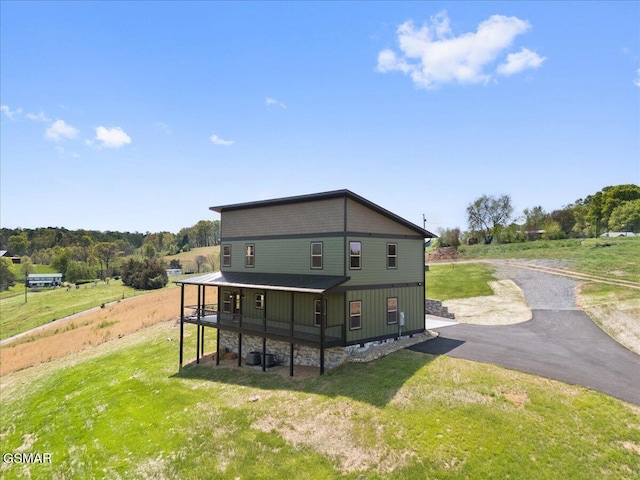 rear view of property featuring driveway and a yard