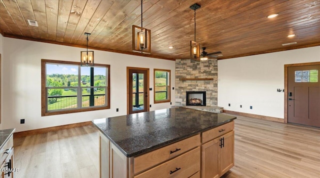 kitchen with baseboards, a fireplace, open floor plan, and light wood finished floors