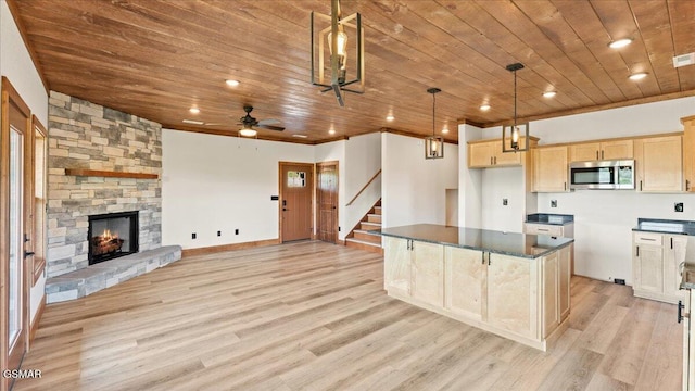 kitchen with wooden ceiling, light wood-style flooring, stainless steel microwave, light brown cabinetry, and dark countertops