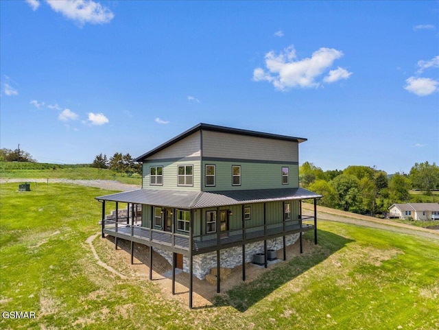 back of house with central AC unit, metal roof, and a lawn