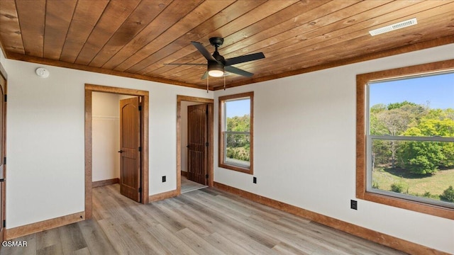 unfurnished bedroom featuring wooden ceiling, a spacious closet, a closet, baseboards, and light wood-type flooring
