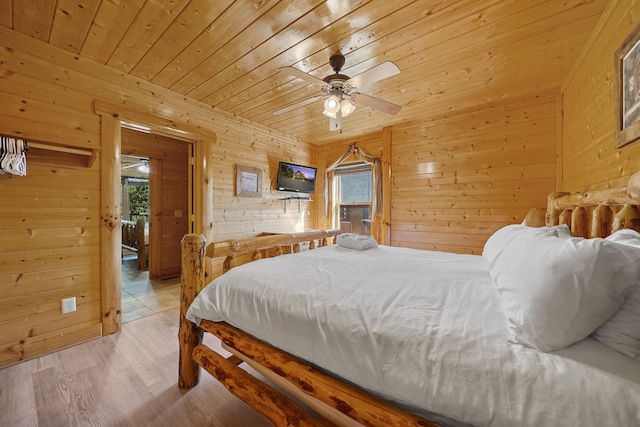 bedroom featuring ceiling fan, wood walls, light hardwood / wood-style flooring, and wooden ceiling