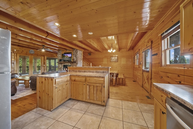 kitchen with light tile patterned flooring, appliances with stainless steel finishes, light brown cabinetry, wood walls, and wooden ceiling