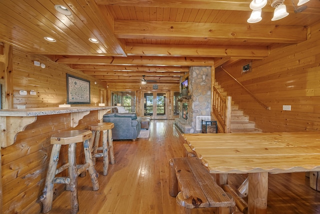 unfurnished dining area with wood walls, wood ceiling, wood-type flooring, indoor bar, and beam ceiling