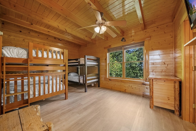 bedroom featuring wooden walls, beamed ceiling, ceiling fan, wood ceiling, and light hardwood / wood-style floors